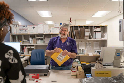 Two employees sharing news and a laugh at the mail room 